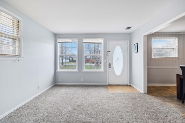 entryway featuring light colored carpet, visible vents, and baseboards