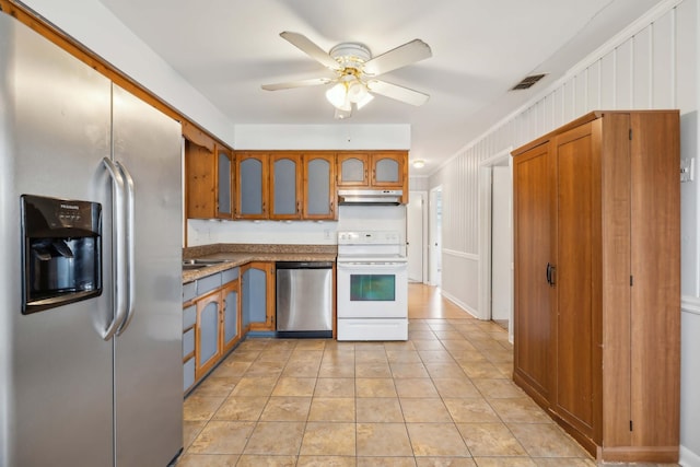 kitchen featuring visible vents, light countertops, appliances with stainless steel finishes, brown cabinetry, and glass insert cabinets