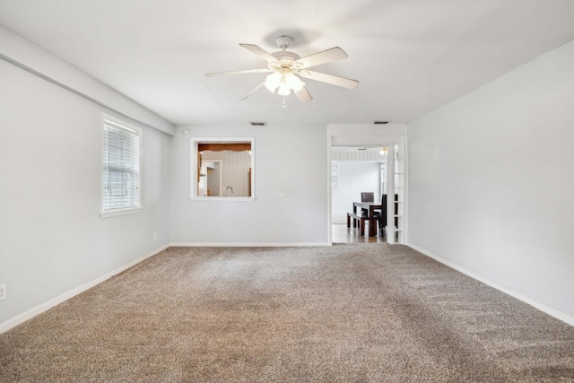 spare room featuring carpet floors, visible vents, baseboards, and ceiling fan