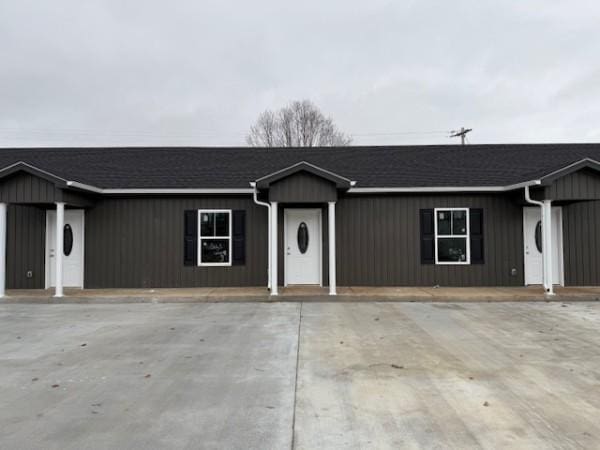 ranch-style house featuring board and batten siding and roof with shingles