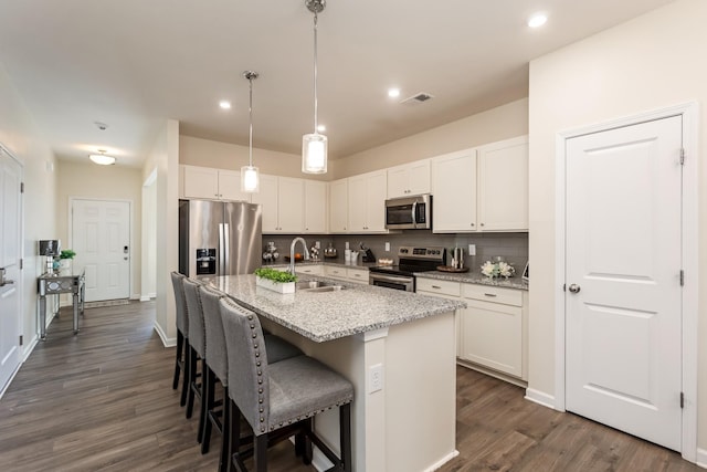 kitchen featuring appliances with stainless steel finishes, a sink, a center island with sink, and white cabinets