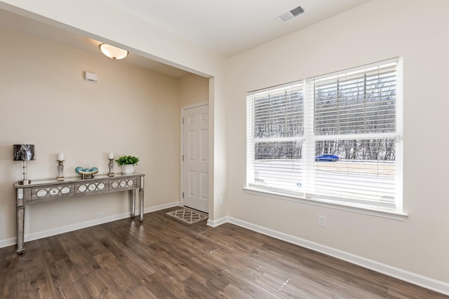 foyer entrance with baseboards, visible vents, and dark wood finished floors