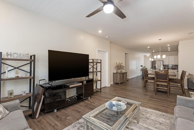 living area with dark wood-style floors, recessed lighting, baseboards, and ceiling fan with notable chandelier