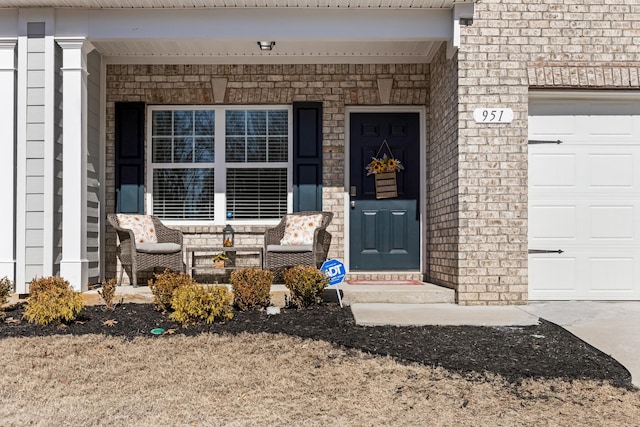 doorway to property featuring a garage, brick siding, and a porch