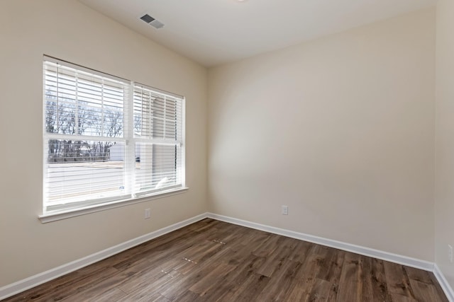 unfurnished room featuring dark wood-style floors, visible vents, and baseboards