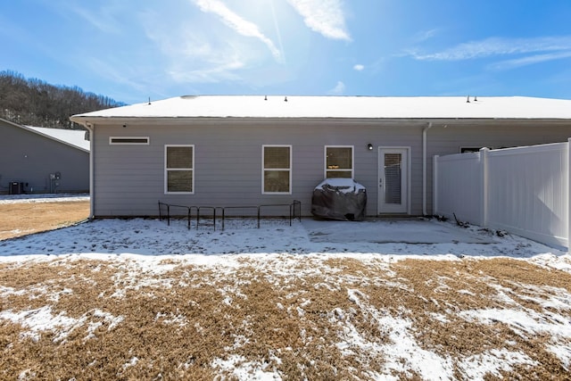 snow covered back of property with fence and central air condition unit