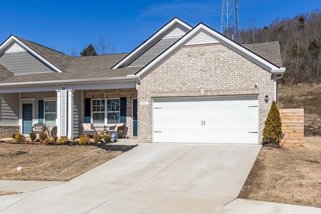 view of front facade with a garage, covered porch, brick siding, and driveway