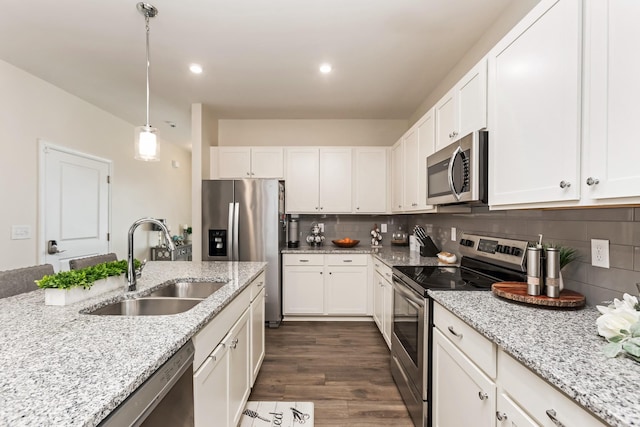 kitchen with a sink, white cabinetry, appliances with stainless steel finishes, backsplash, and decorative light fixtures