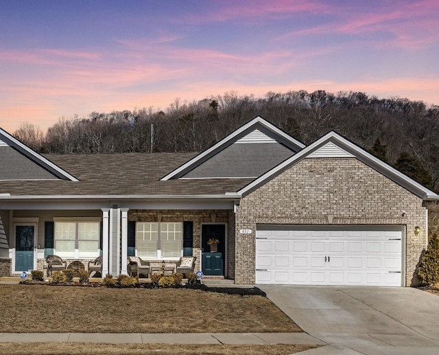 ranch-style home featuring driveway, a shingled roof, an attached garage, and brick siding