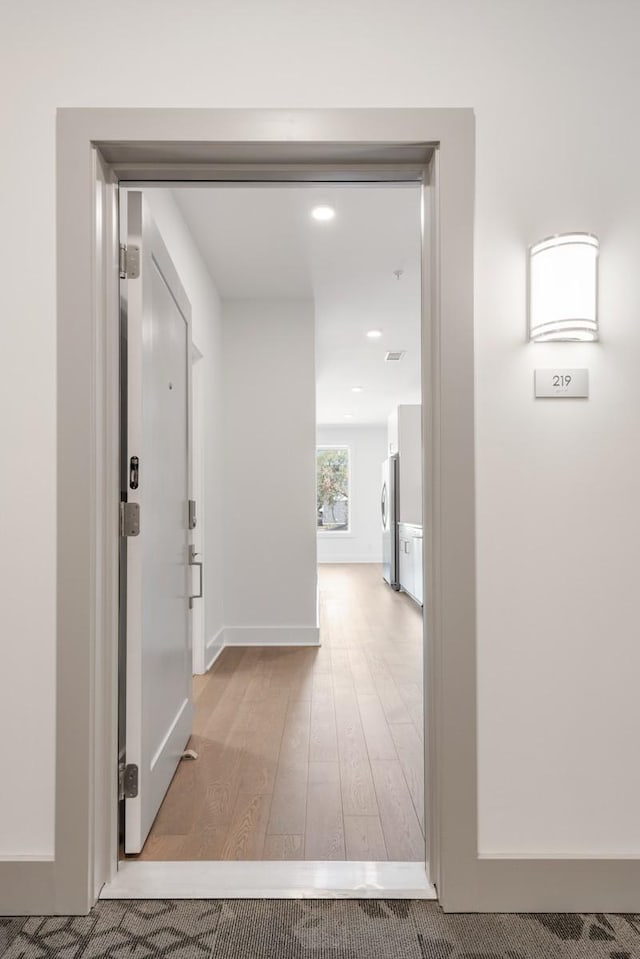 hall with light wood-style flooring and baseboards