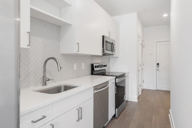 kitchen featuring white cabinets, appliances with stainless steel finishes, light countertops, open shelves, and a sink