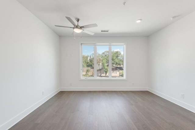 unfurnished room featuring visible vents, dark wood-type flooring, a ceiling fan, and baseboards