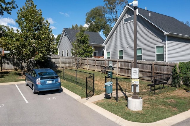 view of side of property featuring uncovered parking, a lawn, and fence