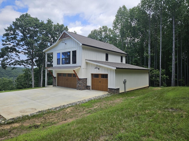 view of home's exterior with concrete driveway, stone siding, an attached garage, a yard, and board and batten siding