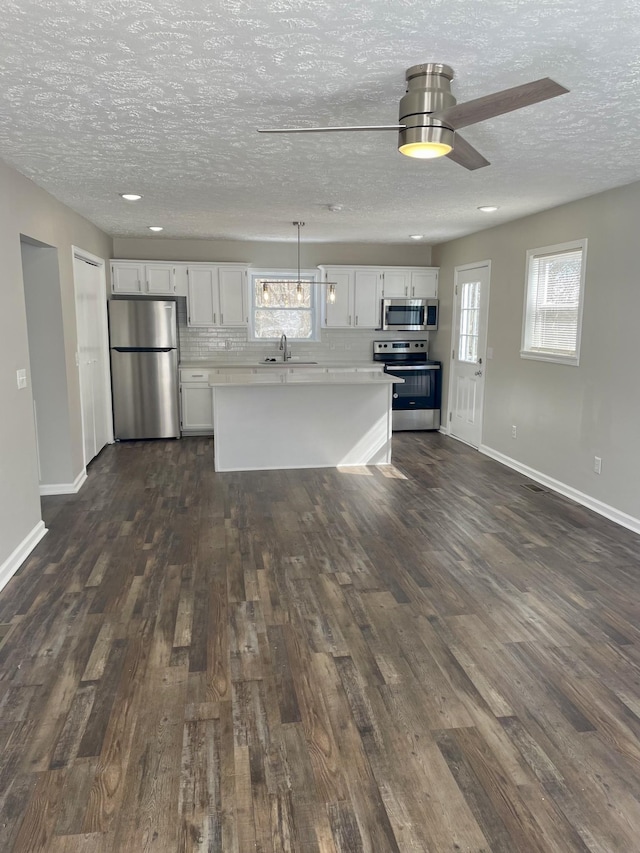 kitchen featuring stainless steel appliances, white cabinetry, light countertops, decorative backsplash, and pendant lighting