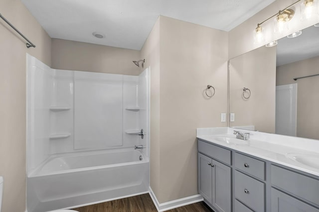 bathroom featuring double vanity, bathtub / shower combination, a sink, wood finished floors, and baseboards