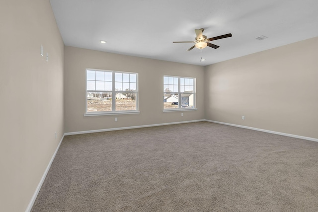 carpeted empty room with visible vents, baseboards, and a ceiling fan