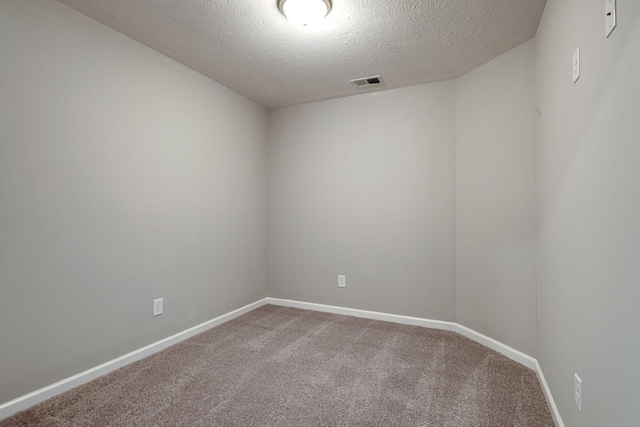 empty room featuring carpet, visible vents, a textured ceiling, and baseboards