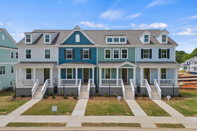 view of property featuring cooling unit, a shingled roof, a residential view, board and batten siding, and a front yard