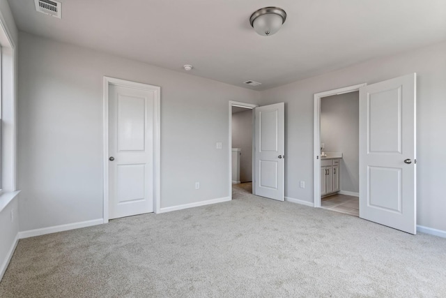 unfurnished bedroom featuring light carpet, connected bathroom, visible vents, and baseboards