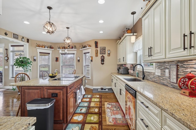 kitchen with dishwasher, a sink, a kitchen island, and light stone countertops