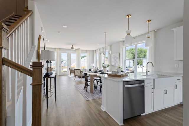 kitchen featuring white cabinets, dishwasher, open floor plan, pendant lighting, and a sink