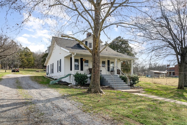 bungalow-style house with a shingled roof, a front yard, covered porch, and driveway