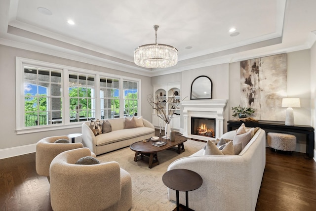 living room with a lit fireplace, a tray ceiling, dark wood finished floors, and crown molding