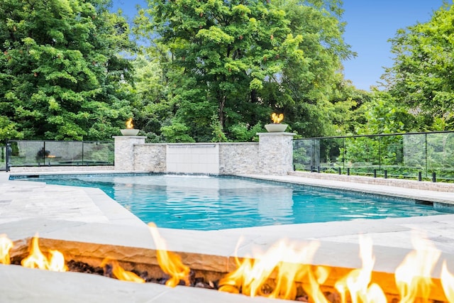 view of pool with an outdoor fire pit, fence, and a fenced in pool