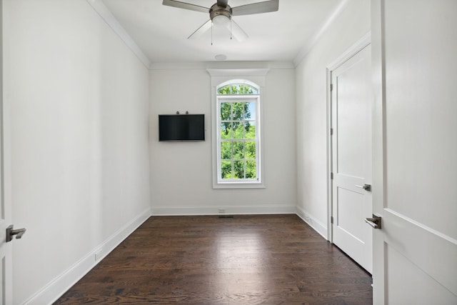 spare room with crown molding, dark wood finished floors, baseboards, and ceiling fan