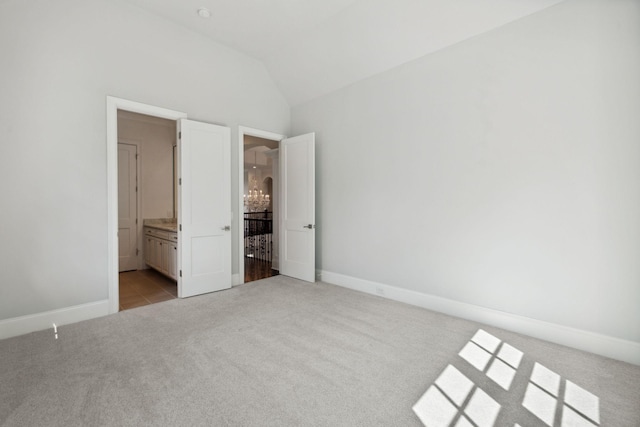 unfurnished bedroom with light carpet, ensuite bathroom, lofted ceiling, and baseboards