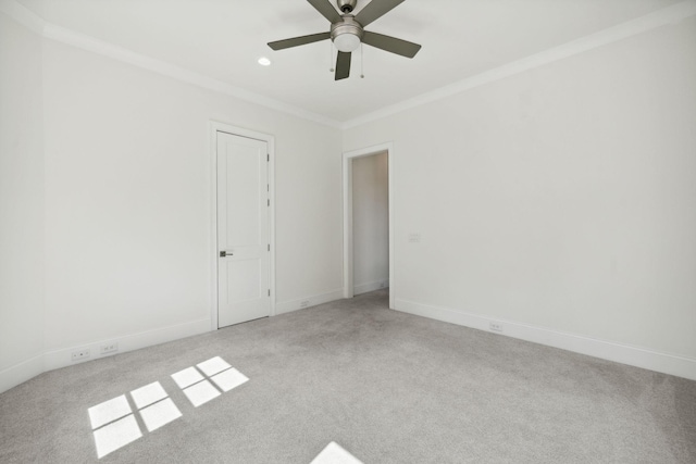 spare room with light colored carpet, crown molding, and baseboards