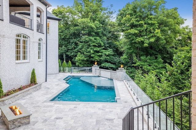 pool featuring an outdoor fire pit, a patio area, and fence