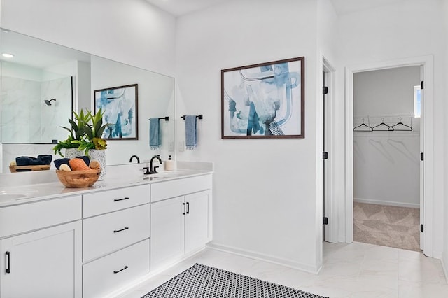 bathroom featuring a walk in closet, marble finish floor, a marble finish shower, double vanity, and a sink