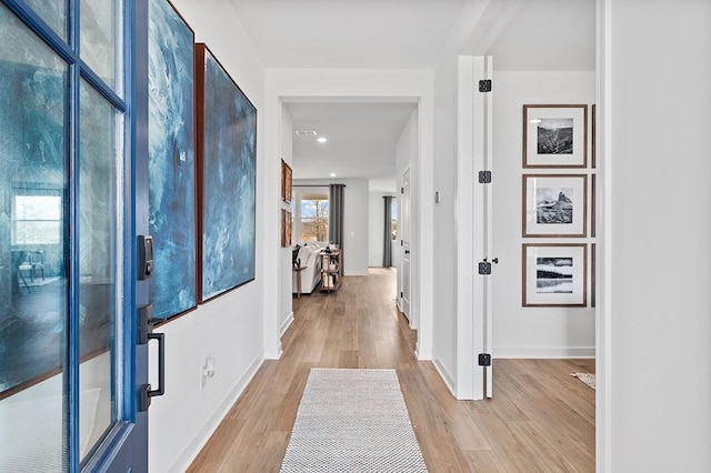 corridor with light wood finished floors and baseboards