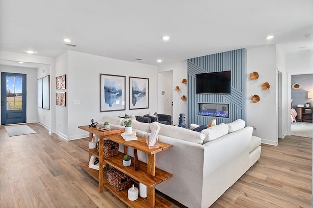 living area with baseboards, light wood-type flooring, visible vents, and recessed lighting