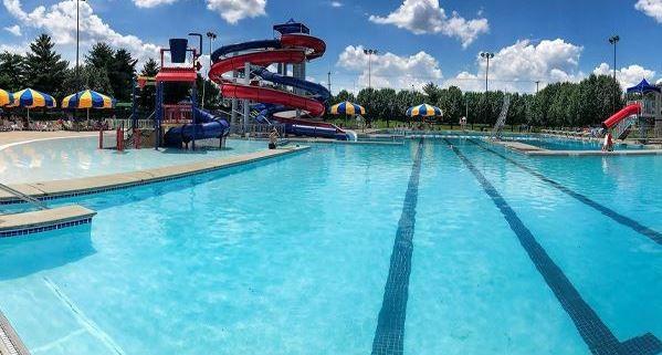 community pool with playground community, a water slide, and a water play area