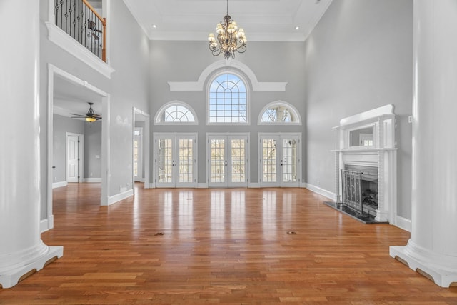 unfurnished living room featuring a fireplace with raised hearth, ornamental molding, wood finished floors, and baseboards