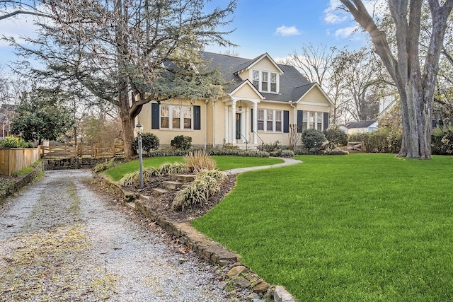 view of front of property featuring a front yard, driveway, fence, and stucco siding