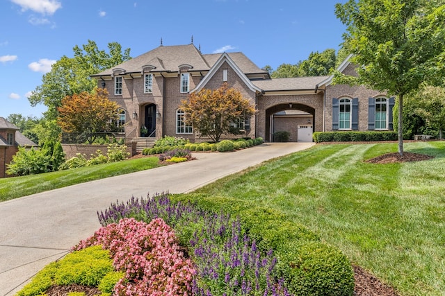 view of front of house featuring driveway, a front lawn, and brick siding