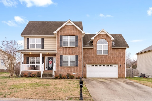 traditional-style home with brick siding, covered porch, an attached garage, a front yard, and driveway