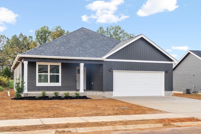 view of front of house featuring central AC unit, driveway, a shingled roof, and an attached garage