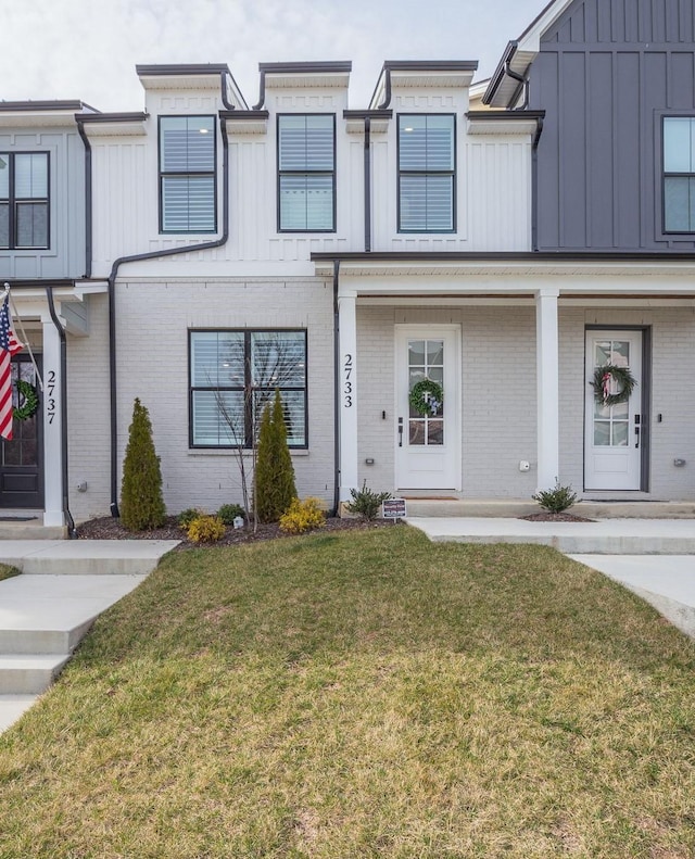 multi unit property with brick siding, board and batten siding, and a front yard