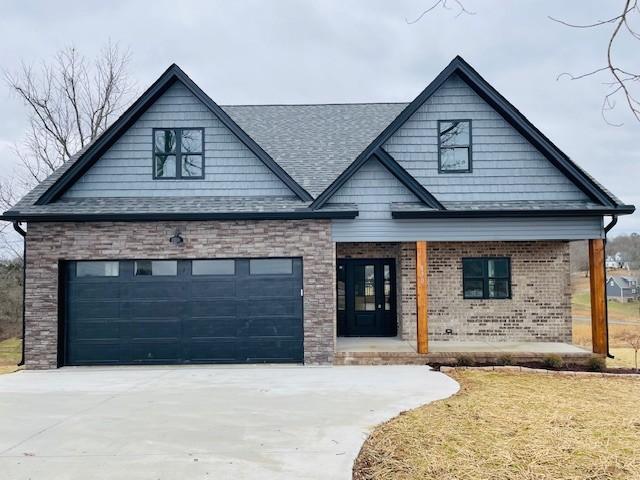 view of front of house featuring a garage, concrete driveway, brick siding, and a front lawn