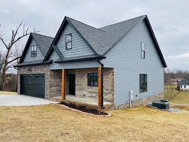 view of front facade featuring brick siding, a shingled roof, concrete driveway, a garage, and a front lawn