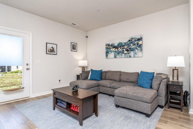 living room with visible vents, light wood-style flooring, and baseboards