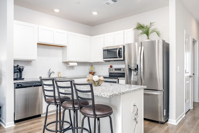 kitchen with white cabinets, light stone counters, and stainless steel appliances