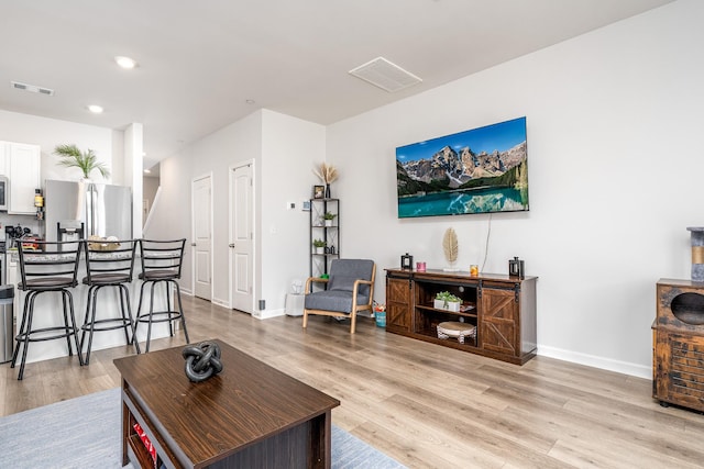 living area with light wood-type flooring, visible vents, and baseboards