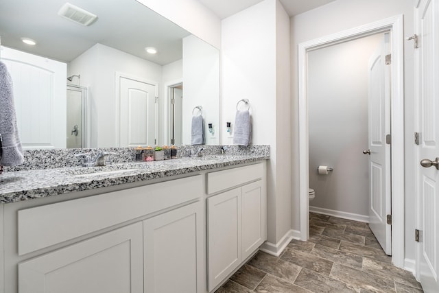 full bath featuring double vanity, visible vents, a sink, a shower stall, and baseboards