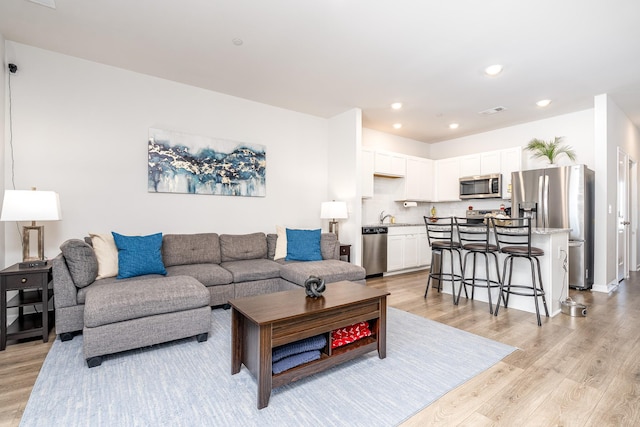 living room featuring light wood-type flooring, visible vents, and recessed lighting